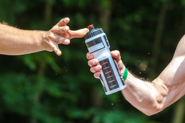 Man holding water bottle and giving it to another man